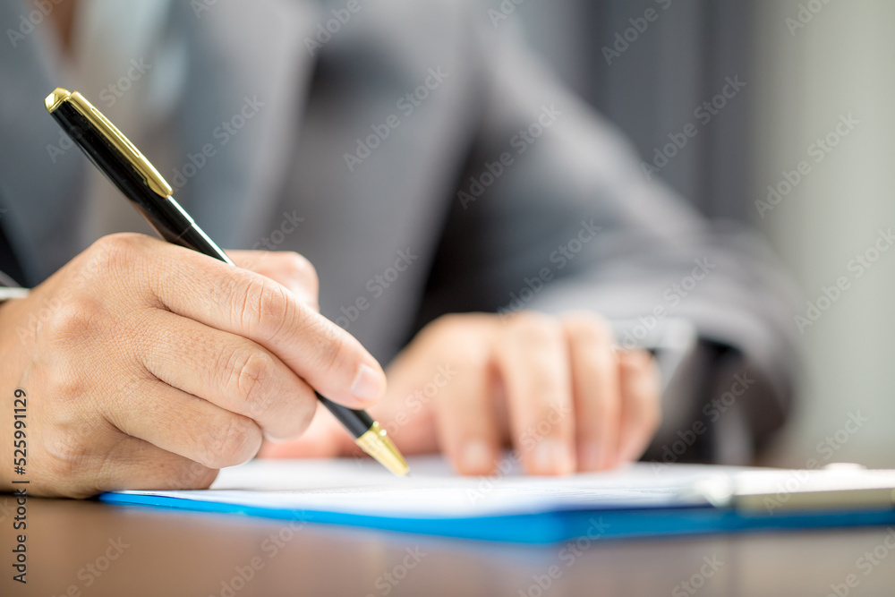 Workplace closeup person professional businesswoman sitting at desk hold pen signing or signature contract paper. Employee woman writing agreement document on paperwork form corporate at work office Workplace closeup person professional businesswoman sitting at desk hold pen signing or signature contract paper. Employee woman writing agreement document on paperwork form corporate at work office