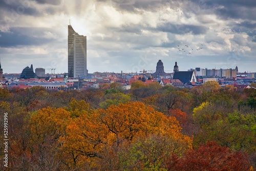 Leipzig Herbstlandschaft Stadtpanorama - Gebäude, Skylines, Hochhäuser während des Sonnenuntergang und die Sonne scheint hinter dem MDR Tower City Hochhaus, daneben das Völkerschlachtdenkmal