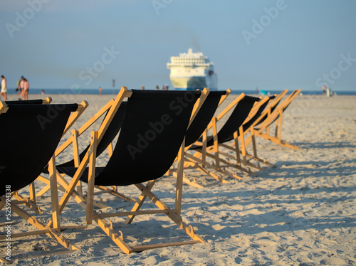Deck chairs on the beach with cruise ship