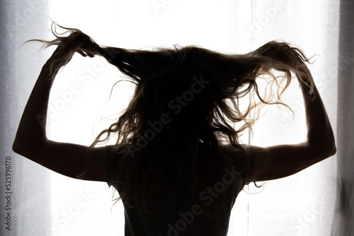 Fotografia silhouette of a woman pulling her hair in a gesture of stress, hysteria, frustra