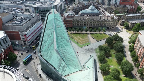 Aerial drone flight over The National Football Museum and Corn Exchange Buildings in Manchester City Centre showing the gardens and rooftops and then slowly revealing a skyline overview over the City photo