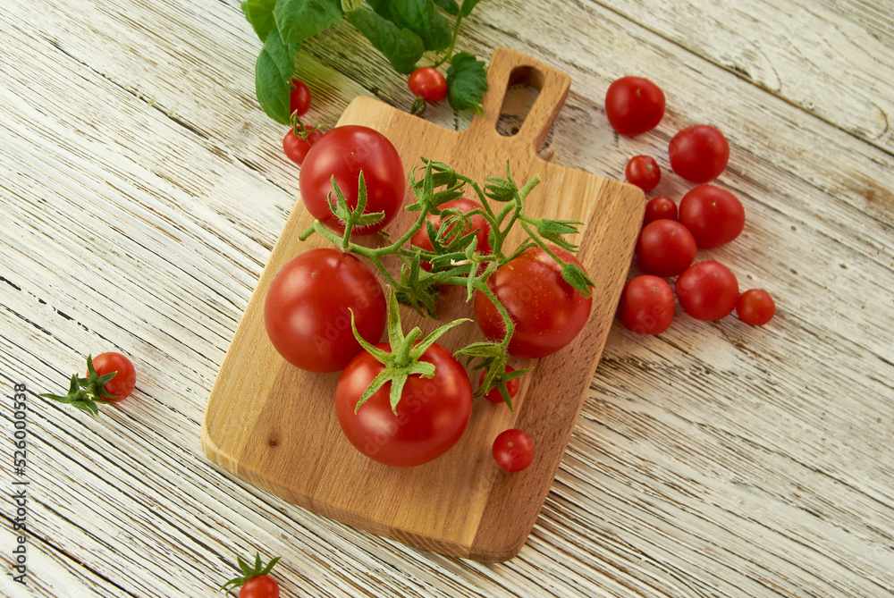 Garden tomatoes on a branch lying on a plank, top view, wooden background. Garden tomatoes on a branch lying on a plank, top view, wooden background.