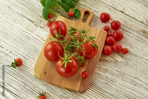 Garden tomatoes on a branch lying on a plank, top view, wooden background.