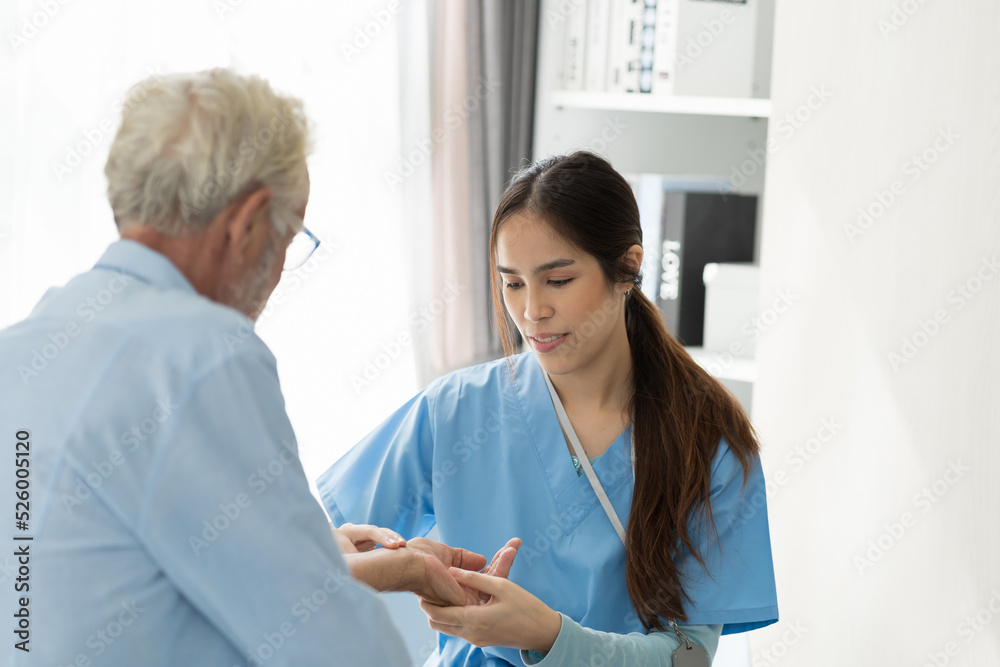Obraz premium Young female nurse caring senior man sitting in room at hospital. Caring Asian nurse taking care of elderly man in room at nursing home. People and health care concept