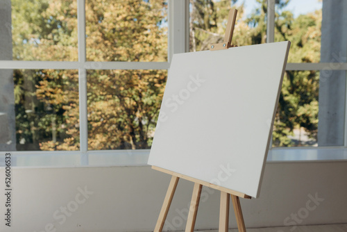 Wooden easel with white canvas. Place for text