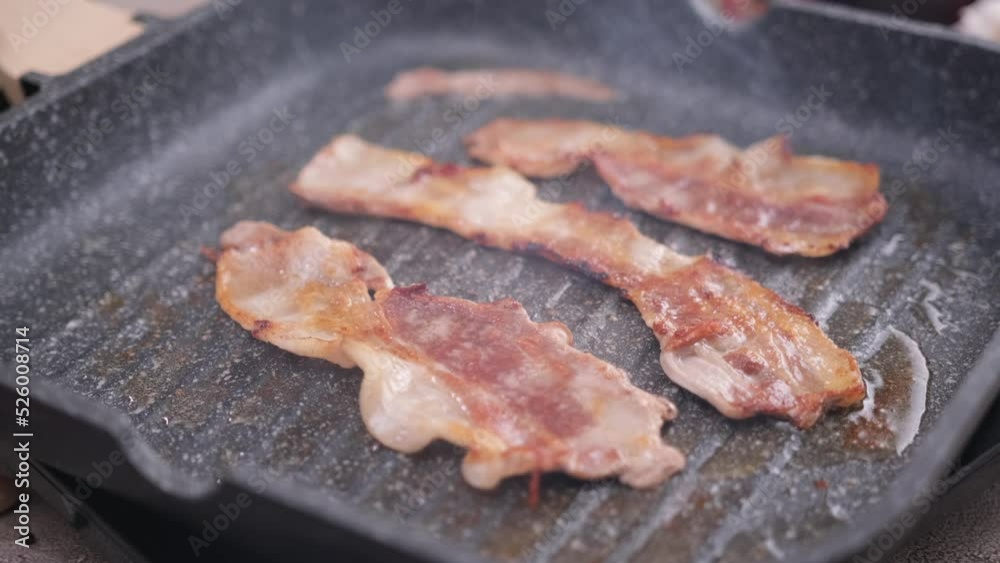 cooking Pieces of flavorful sliced organic bacon fried in grill pan cooking Pieces of flavorful sliced organic bacon fried in grill pan