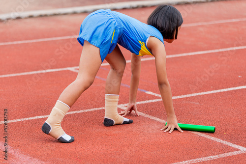 A child athlete runs a race wearing only socks.