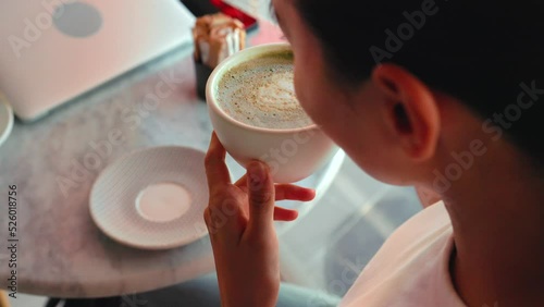 Top view of a girl taking a sip of matcha green tea latte a latte art on it. Healthy food and drinks