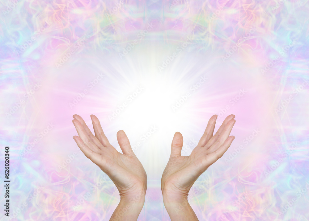 Sending you high frequency love and light healing energy - open female hands with white light between against beautiful pale multicoloured energy field background and copy space 
