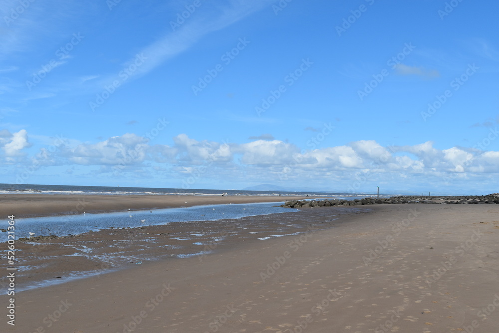 Dramatic cloudy sky over the sea with waves crashing onto the beach. Taken in Fleetwood Lancashire England. 