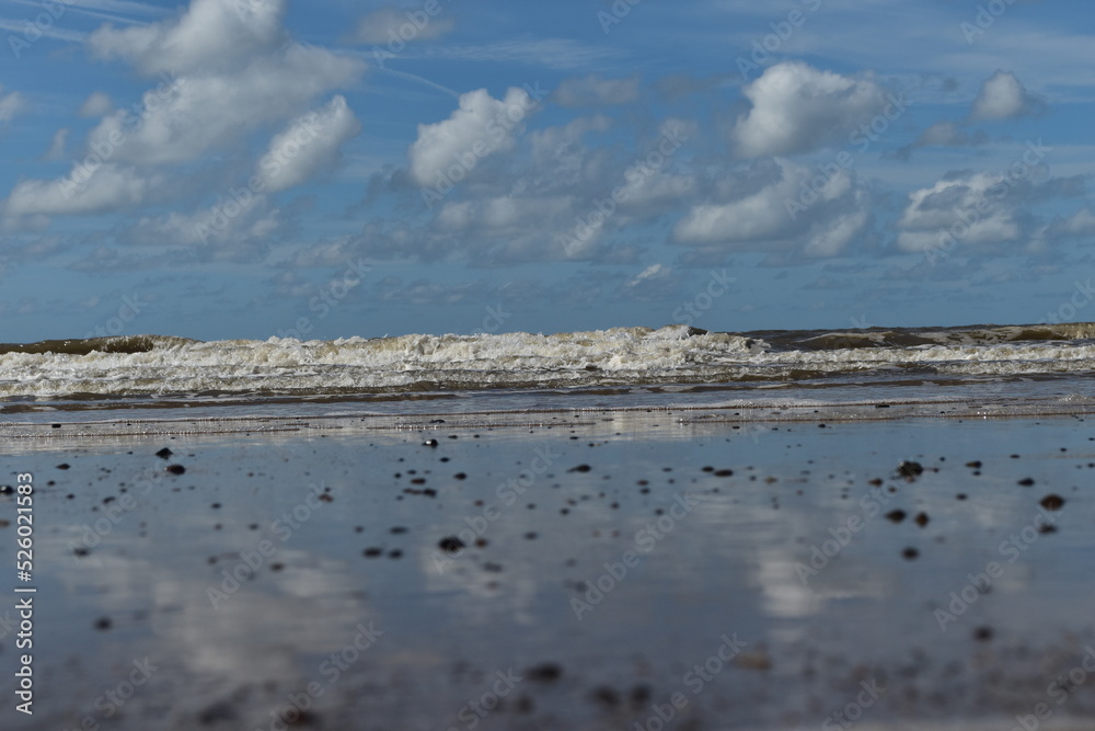 Dramatic cloudy sky over the sea with waves crashing onto the beach. Taken in Fleetwood Lancashire England. 