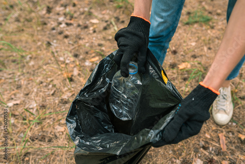 People cleaning up the forest and collecting trash, a woman is picking up a plastic bottle