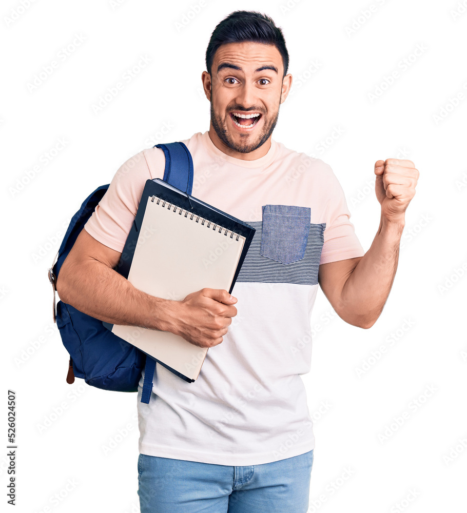 Young handsome man wearing student backpack and notebook screaming proud, celebrating victory and success very excited with raised arms Young handsome man wearing student backpack and notebook screaming proud, celebrating victory and success very excited with raised arms