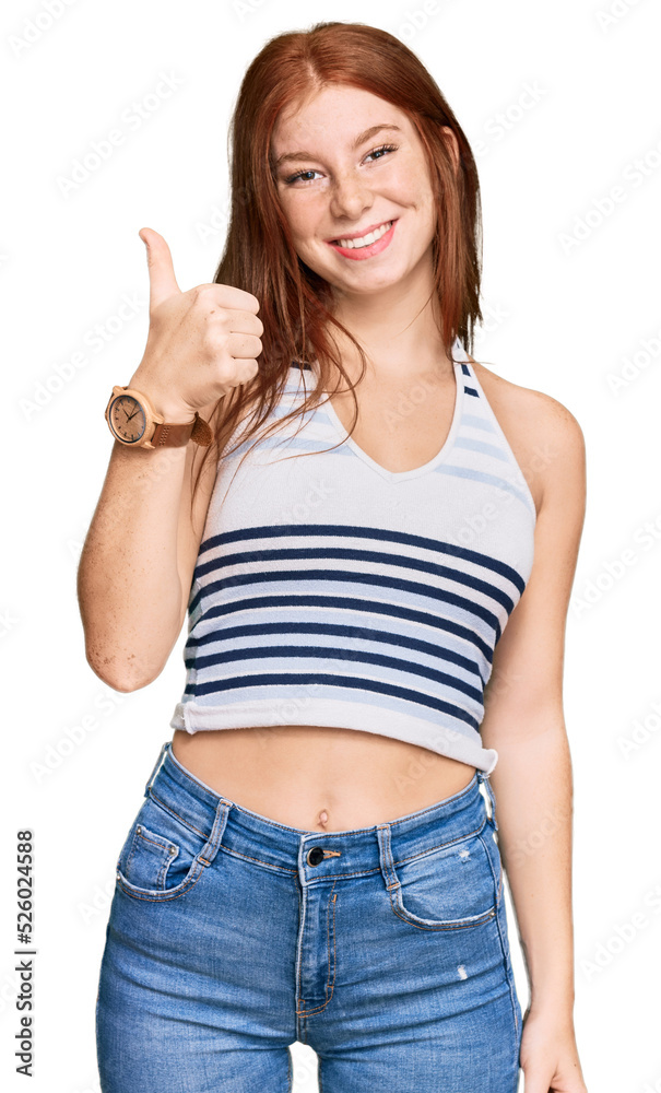 Young read head woman wearing casual clothes doing happy thumbs up gesture with hand. approving expression looking at the camera showing success. Young read head woman wearing casual clothes doing happy thumbs up gesture with hand. approving expression looking at the camera showing success.