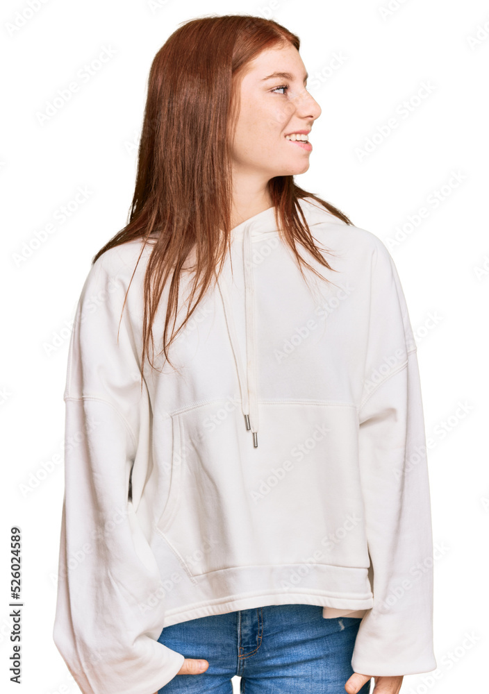 Young read head woman wearing casual sweatshirt looking away to side with smile on face, natural expression. laughing confident. Young read head woman wearing casual sweatshirt looking away to side with smile on face, natural expression. laughing confident.