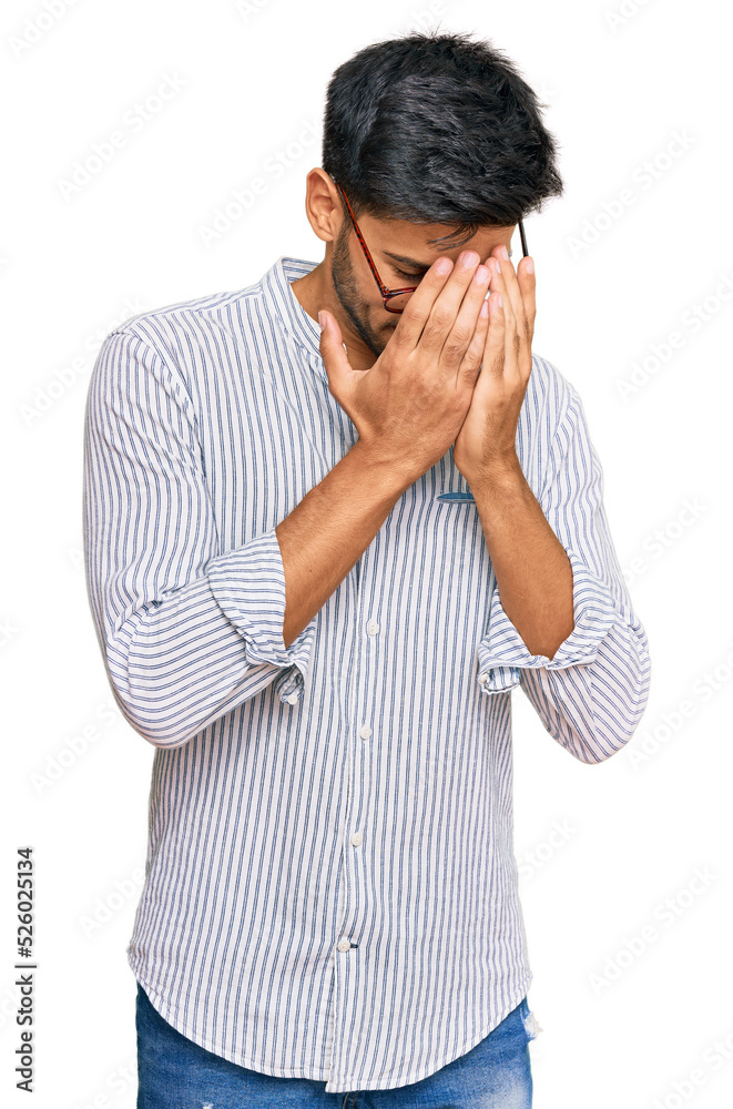 Young handsome man wearing casual clothes and glasses with sad expression covering face with hands while crying. depression concept. Young handsome man wearing casual clothes and glasses with sad expression covering face with hands while crying. depression concept.