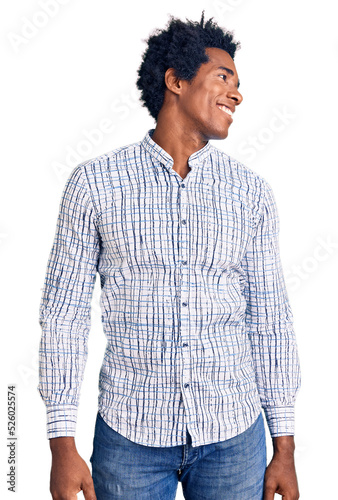 Handsome african american man with afro hair wearing casual clothes looking away to side with smile on face, natural expression. laughing confident.