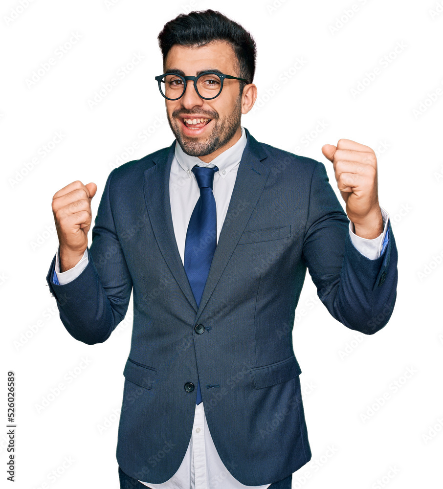 Hispanic man with beard wearing business suit and tie screaming proud, celebrating victory and success very excited with raised arms Hispanic man with beard wearing business suit and tie screaming proud, celebrating victory and success very excited with raised arms