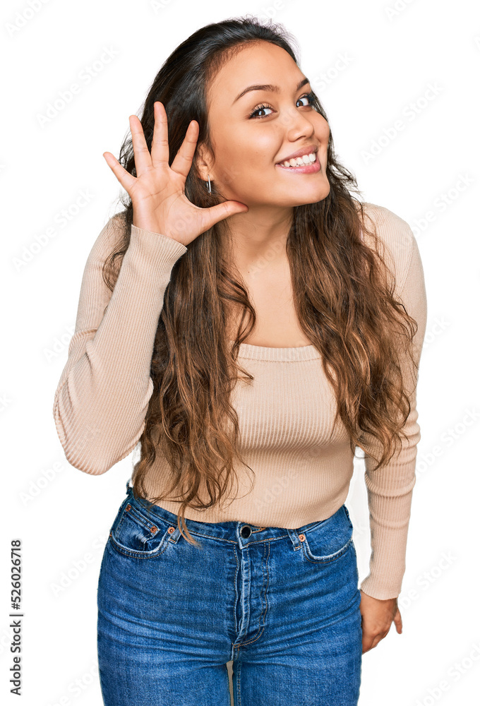 Young hispanic girl wearing casual clothes smiling with hand over ear listening an hearing to rumor or gossip. deafness concept. Young hispanic girl wearing casual clothes smiling with hand over ear listening an hearing to rumor or gossip. deafness concept.