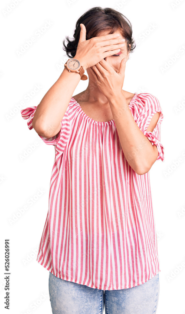 Beautiful young woman with short hair wearing casual summer clothes covering eyes and mouth with hands, surprised and shocked. hiding emotion Beautiful young woman with short hair wearing casual summer clothes covering eyes and mouth with hands, surprised and shocked. hiding emotion