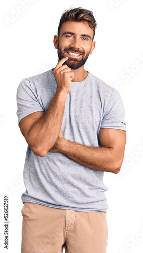 Young hispanic man wearing casual clothes looking confident at the camera smiling with crossed arms and hand raised on chin. thinking positive.