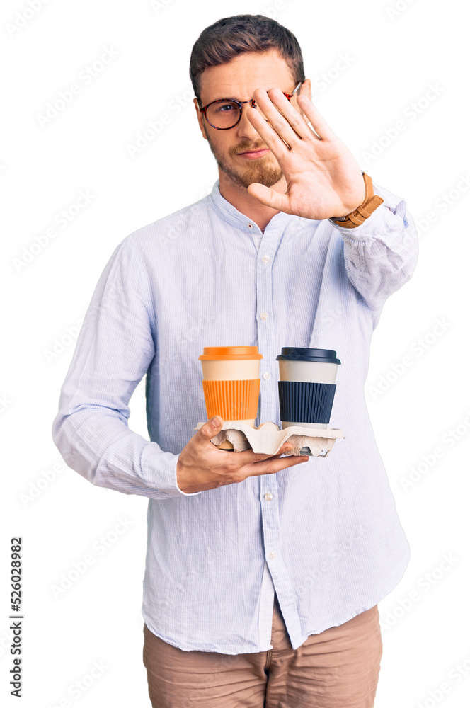 Handsome young man with bear holding takeaway cup of coffee with open hand doing stop sign with serious and confident expression, defense gesture Handsome young man with bear holding takeaway cup of coffee with open hand doing stop sign with serious and confident expression, defense gesture