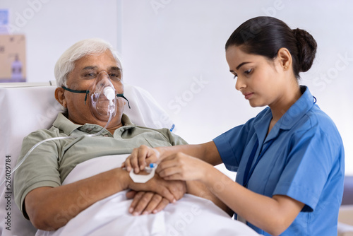 Female nurse injecting needle in hand of elderly patient at hospital
