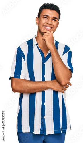 Young arab man wearing casual clothes looking confident at the camera with smile with crossed arms and hand raised on chin. thinking positive.