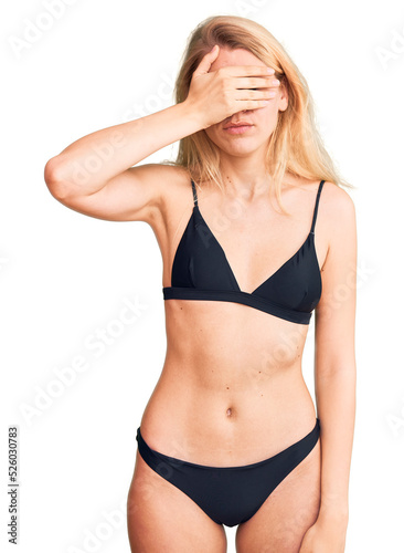 Young beautiful blonde woman wearing bikini covering eyes with hand, looking serious and sad. sightless, hiding and rejection concept