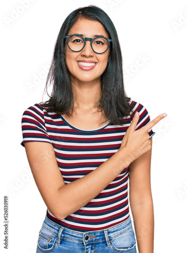 Fototapeta Naklejka Na Ścianę i Meble -  Beautiful asian young woman wearing casual clothes and glasses cheerful with a smile of face pointing with hand and finger up to the side with happy and natural expression on face