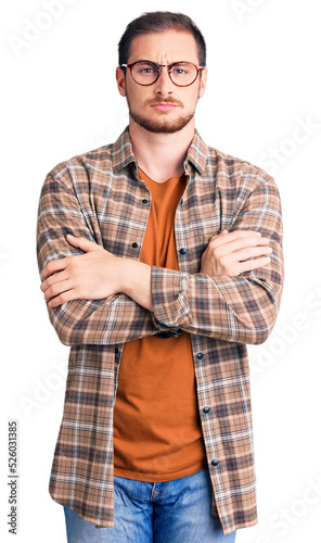 Young handsome caucasian man wearing casual clothes and glasses skeptic and nervous, disapproving expression on face with crossed arms. negative person.