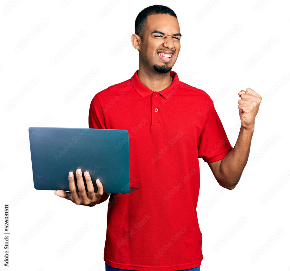 Young african american man working using computer laptop screaming proud, celebrating victory and success very excited with raised arms Young african american man working using computer laptop screaming proud, celebrating victory and success very excited with raised arms