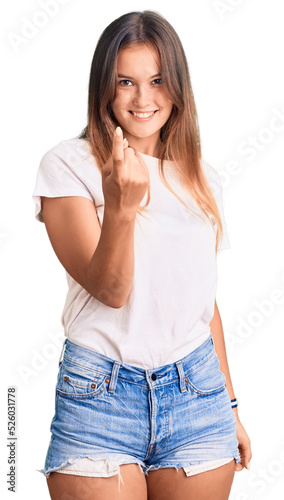 Beautiful caucasian woman wearing casual white tshirt beckoning come here gesture with hand inviting welcoming happy and smiling