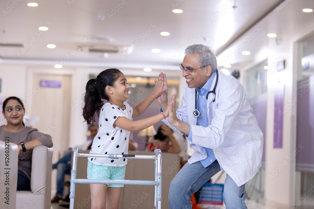 Doctor giving high five disable girl at hospital