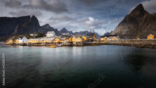 Rorbu houses of Sakrisoy fishing village on a cloudy day with mountains in the background photo