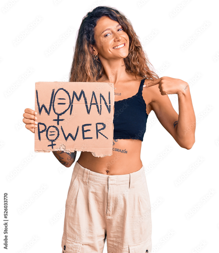 Young hispanic woman with tattoo holding woman power banner pointing finger to one self smiling happy and proud Young hispanic woman with tattoo holding woman power banner pointing finger to one self smiling happy and proud