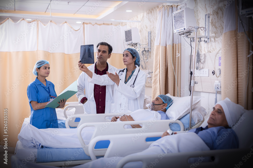 Fototapeta premium Doctor examining senior patient in critical health conditions and examining the x ray in the intensive care unit 