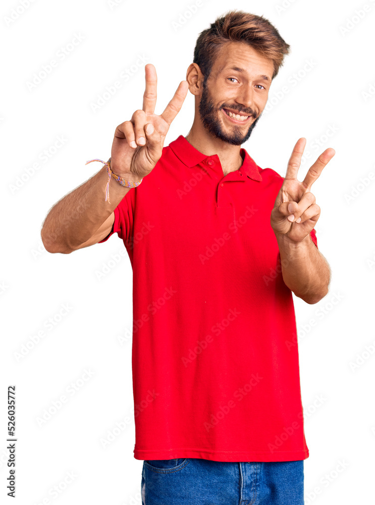 Handsome blond man with beard wearing casual clothes smiling looking to the camera showing fingers doing victory sign. number two. Handsome blond man with beard wearing casual clothes smiling looking to the camera showing fingers doing victory sign. number two.