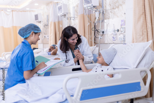 Photography Friendly female doctor examining small girl in bed in hospital