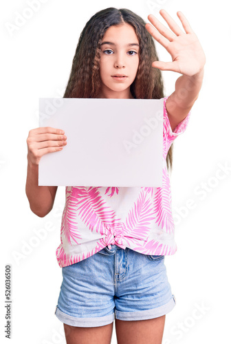 Cute hispanic child girl holding blank empty banner with open hand doing stop sign with serious and confident expression, defense gesture