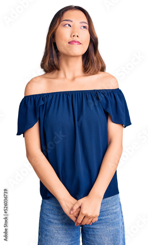 Young beautiful chinese girl wearing casual clothes smiling looking to the side and staring away thinking.