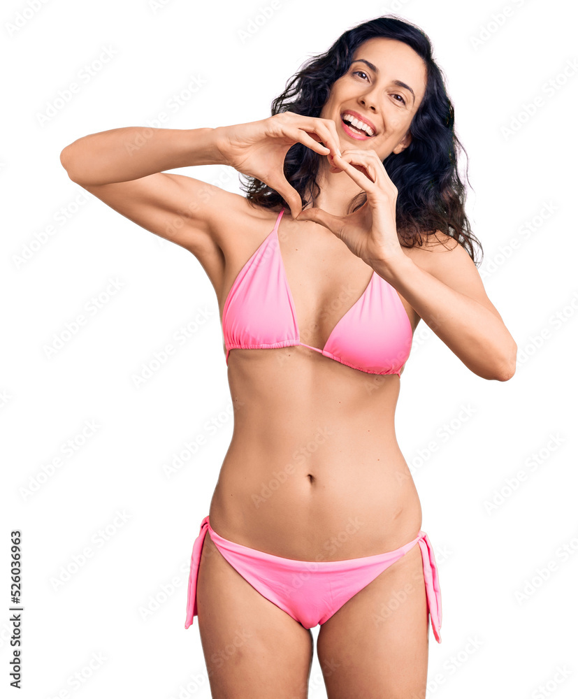 Young beautiful hispanic woman wearing bikini smiling in love doing heart symbol shape with hands. romantic concept. Young beautiful hispanic woman wearing bikini smiling in love doing heart symbol shape with hands. romantic concept.