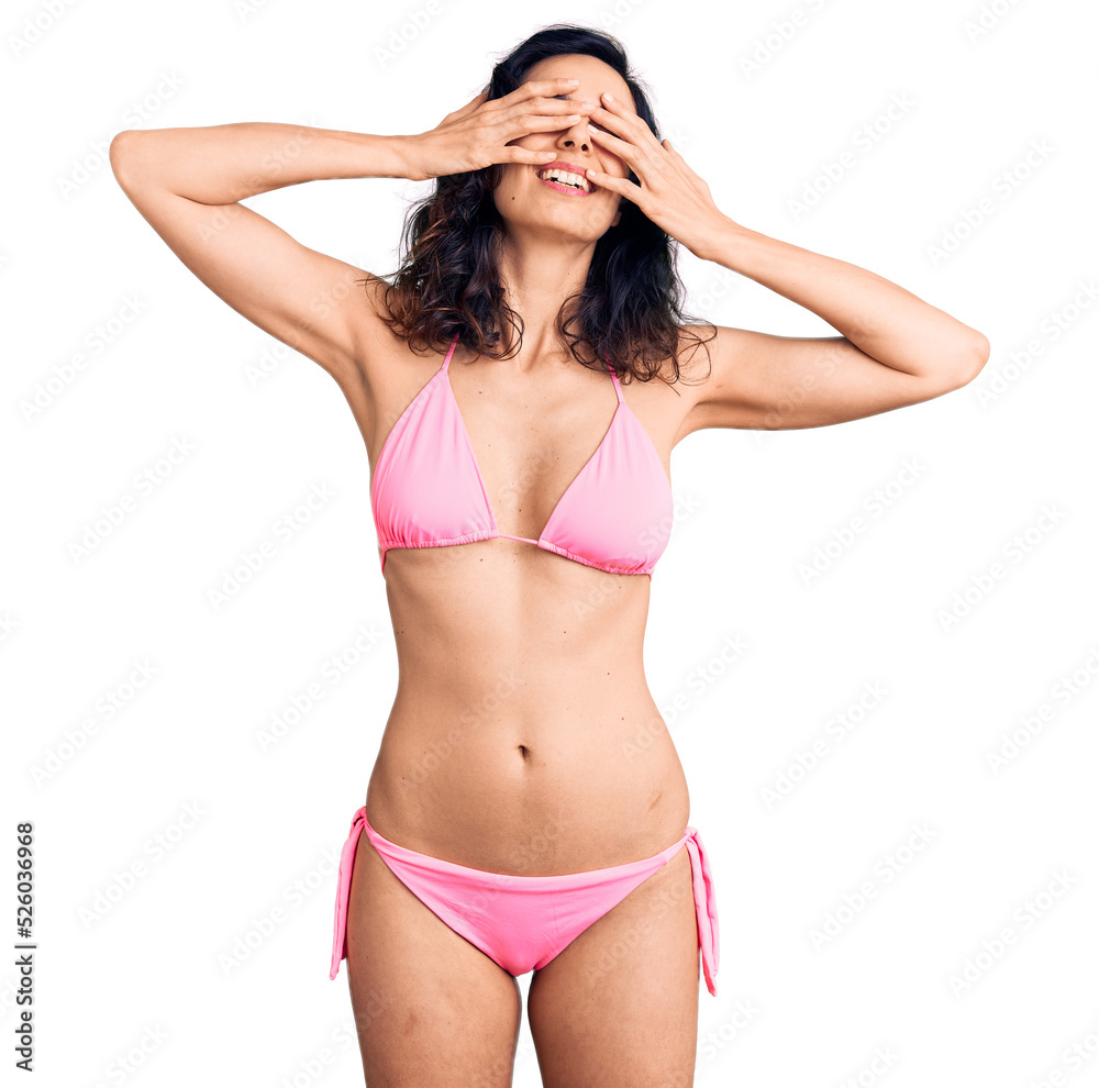 Young beautiful hispanic woman wearing bikini covering eyes with hands smiling cheerful and funny. blind concept. Young beautiful hispanic woman wearing bikini covering eyes with hands smiling cheerful and funny. blind concept.