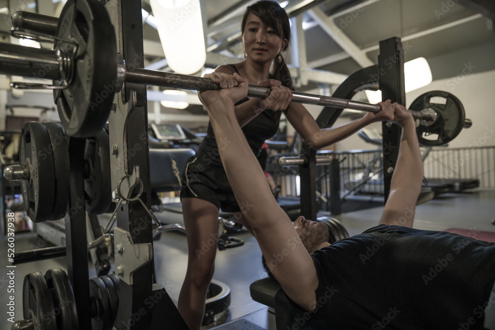 man exercising with dumbbell help by his coach man exercising with dumbbell help by his coach