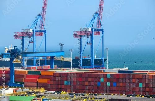infrastructure of an industrial seaport, container warehouse for loading onto a container ship, sea and cranes, the concept of sea cargo transportation