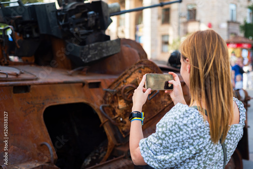 girl takes a photo on the phone of a burnt Russian tank on the street of Kyiv, Ukraine. independence Day of Ukraine. 23.08.22