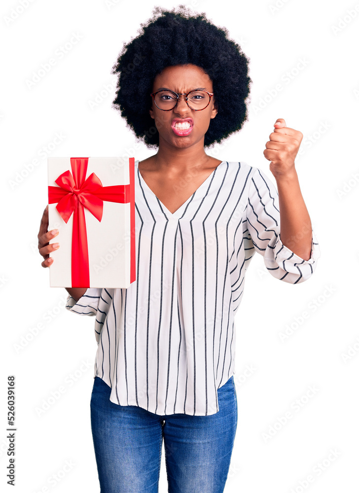 Young african american woman holding gift annoyed and frustrated shouting with anger, yelling crazy with anger and hand raised Young african american woman holding gift annoyed and frustrated shouting with anger, yelling crazy with anger and hand raised