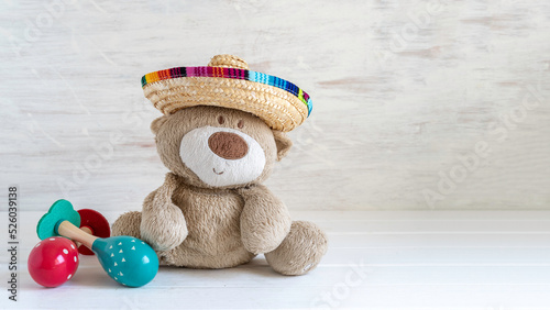 Bear toy in sombrero and maracas for The Cry of Dolores (Mexico's Independence Day) on white wooden background with copy space. photo