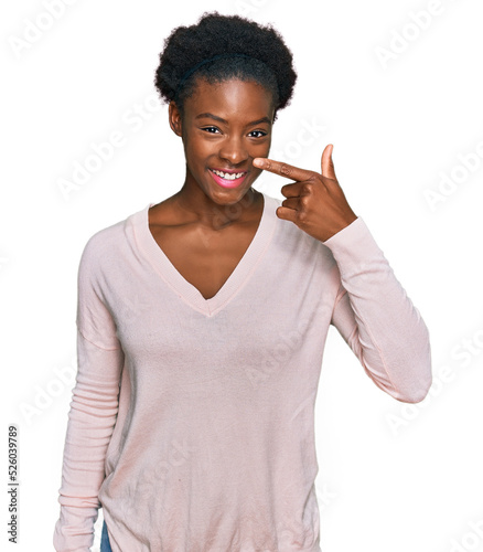 Young african american girl wearing casual clothes pointing with hand finger to face and nose, smiling cheerful. beauty concept