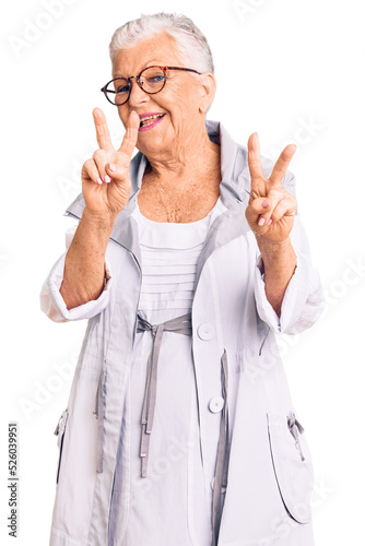 Senior beautiful woman with blue eyes and grey hair wearing casual clothes and glasses smiling looking to the camera showing fingers doing victory sign. number two. © Krakenimages.com